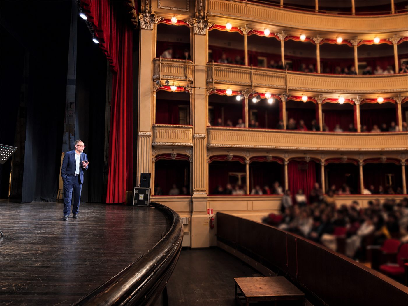 Giammaria de Paulis sul palco di un teatro davanti a una platea gremita